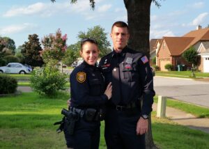 Male and female Cops standing next to tree